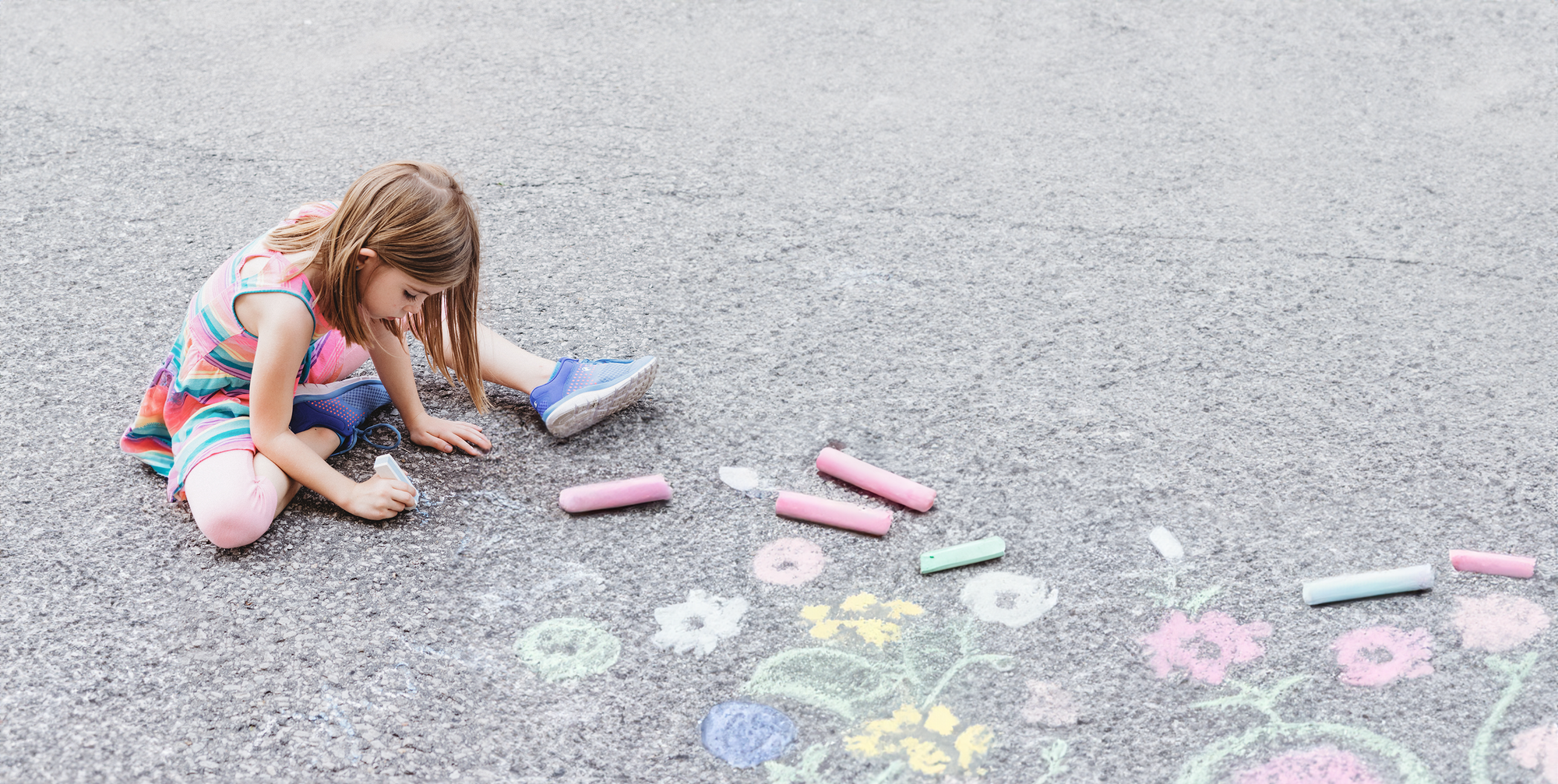 Girl drawing with chalk on the pavement